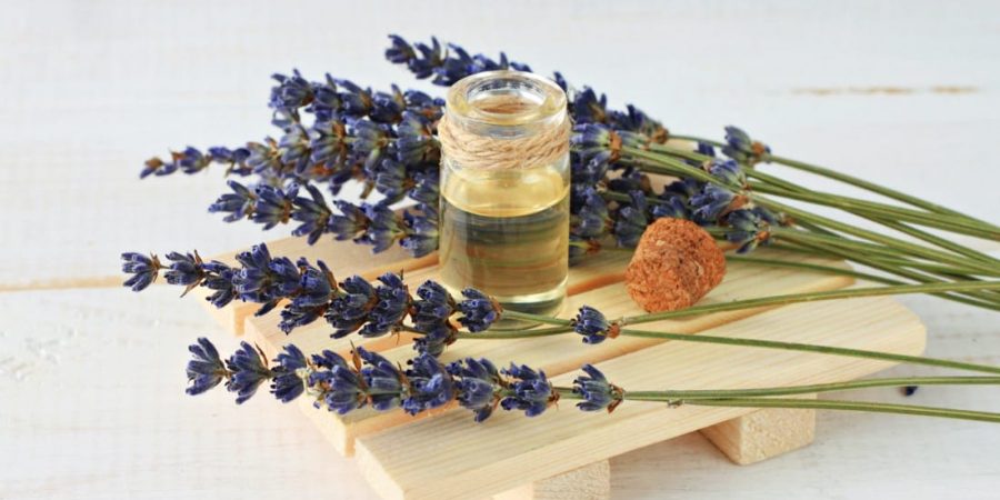 The linalool terpene sits on a wood board draped by lavender flowers.
